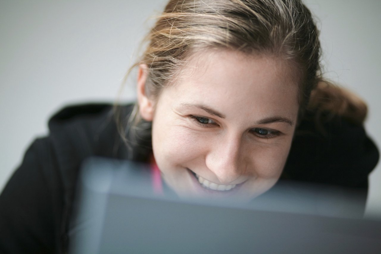 woman smiling behind laptop
