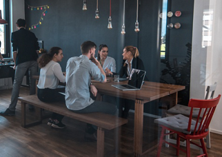 Male and female web designers seen through glass in cafeteria. Business professionals are sitting at table during break in office. They are at workplace.