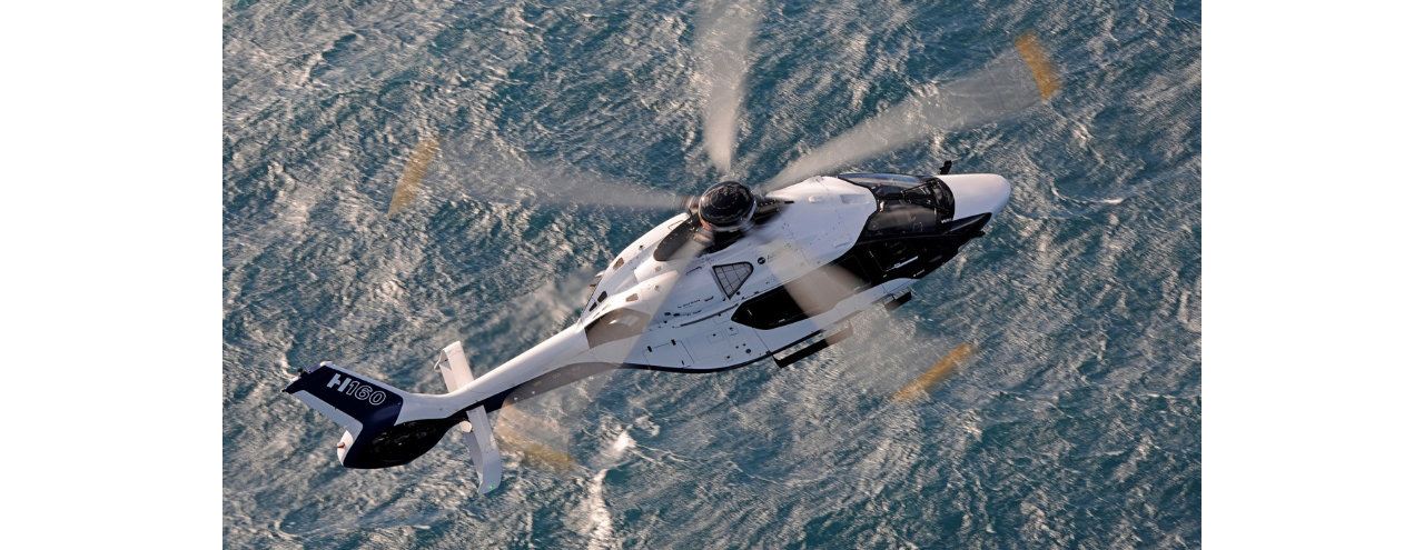Aerial view of an Airbus H160 helicopter flying over water 