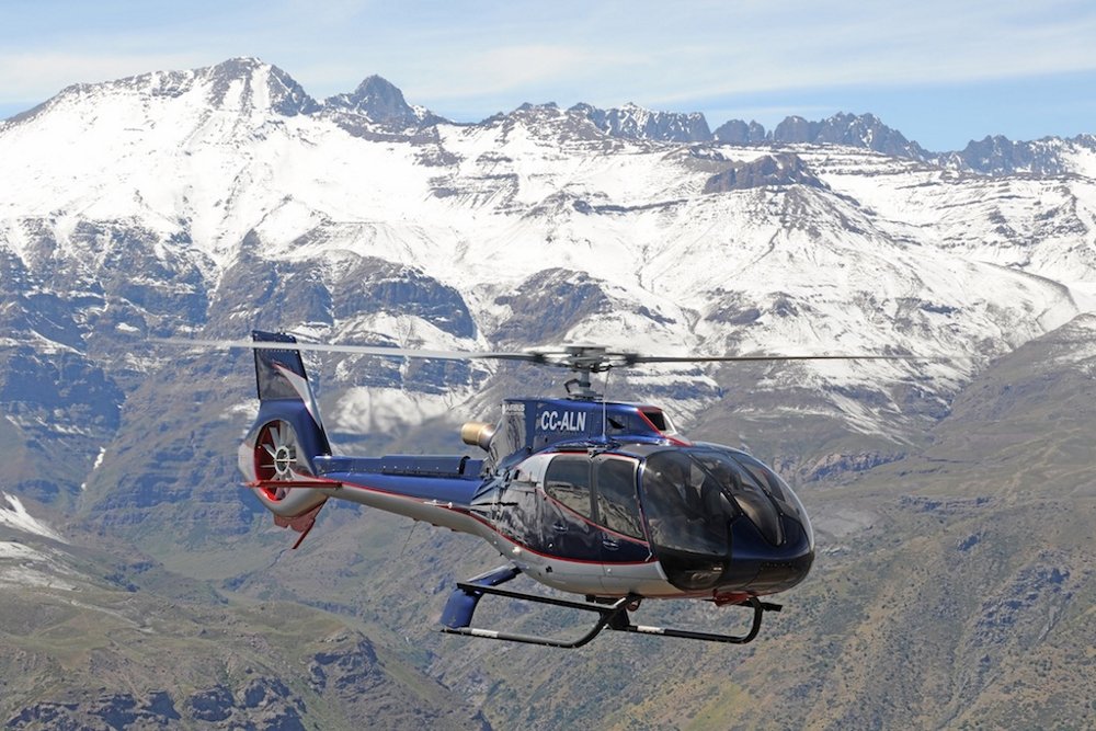 An Airbus H130 helicopter flies near mountainous terrain in Chile. 