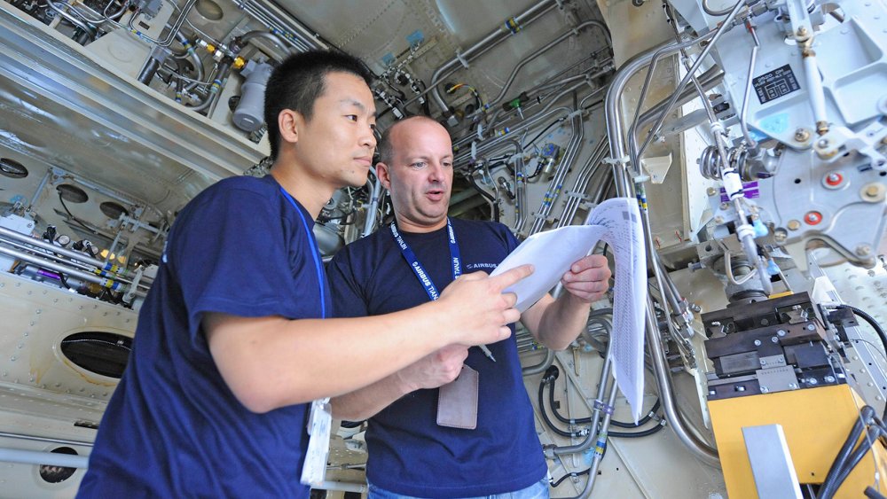 Two Airbus employees review documentation at the company’s final assembly line in Tianjin, China.