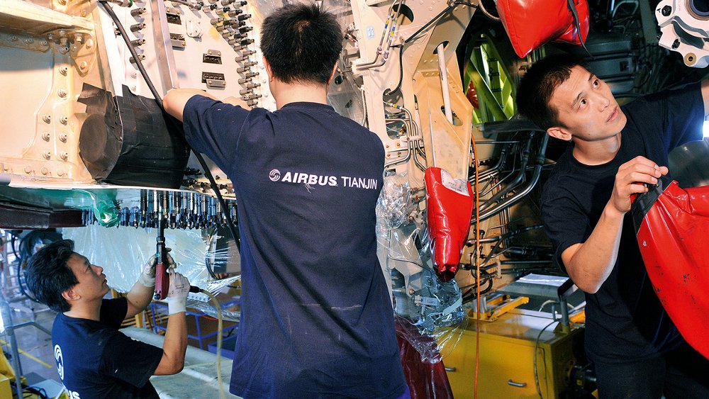 Three Airbus employees are shown working at the company’s final assembly line in Tianjin, China.