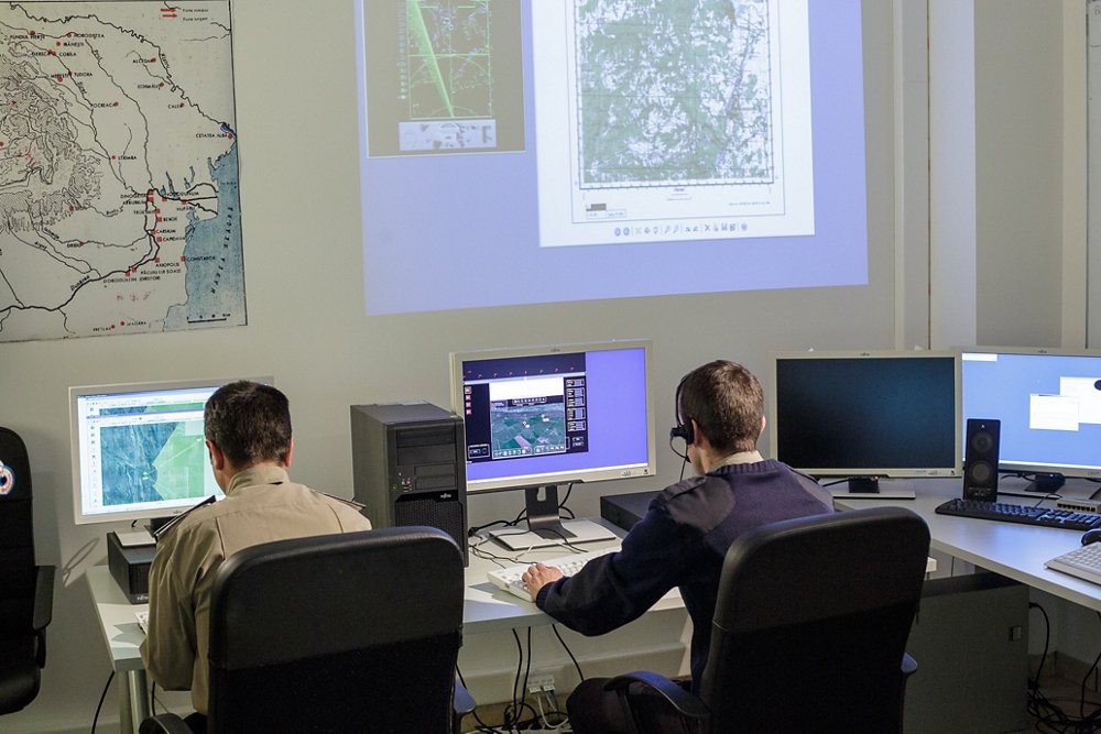Two employees working on computers in a border security command and control centre.  