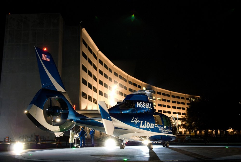 A PennState Health Life Lion AS365 N3+ used for helicopter emergency medical service (HEMS) on a helipad at night.  