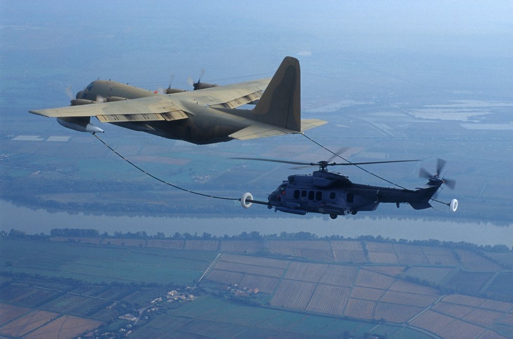 An Airbus-built AS532 A2 helicopter is shown during in-flight refueling tests with an aerial tanker aircraft.  