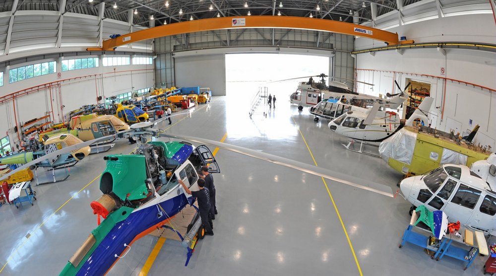 A fisheye lens view inside an Airbus Helicopters maintenance facility with multiple rotorcraft. 