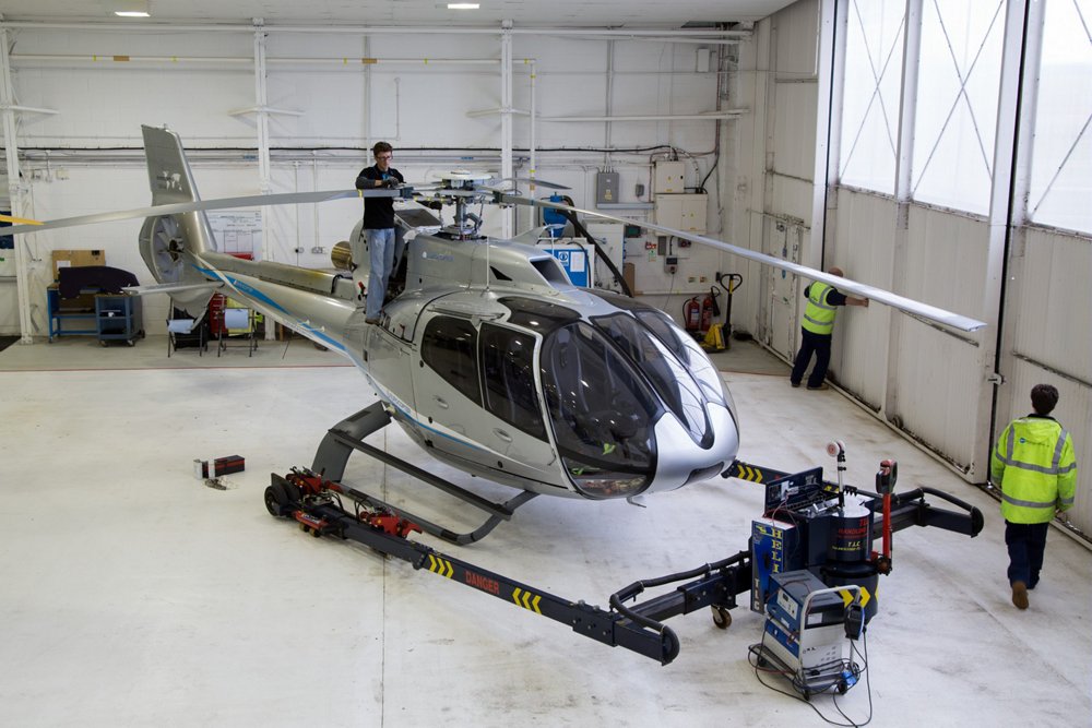 An Airbus H130 helicopter undergoes maintenance checks in a hangar 