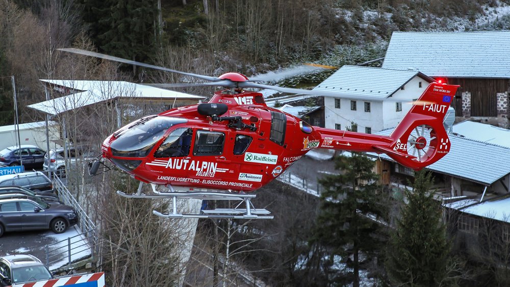 An Airbus H135 helicopter operated by Aiut Alpin Dolomites for rescue missions flies in a residential area  