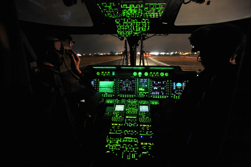 The NH90 helicopter’s flight controls and panels are illuminated inside the cockpit. 