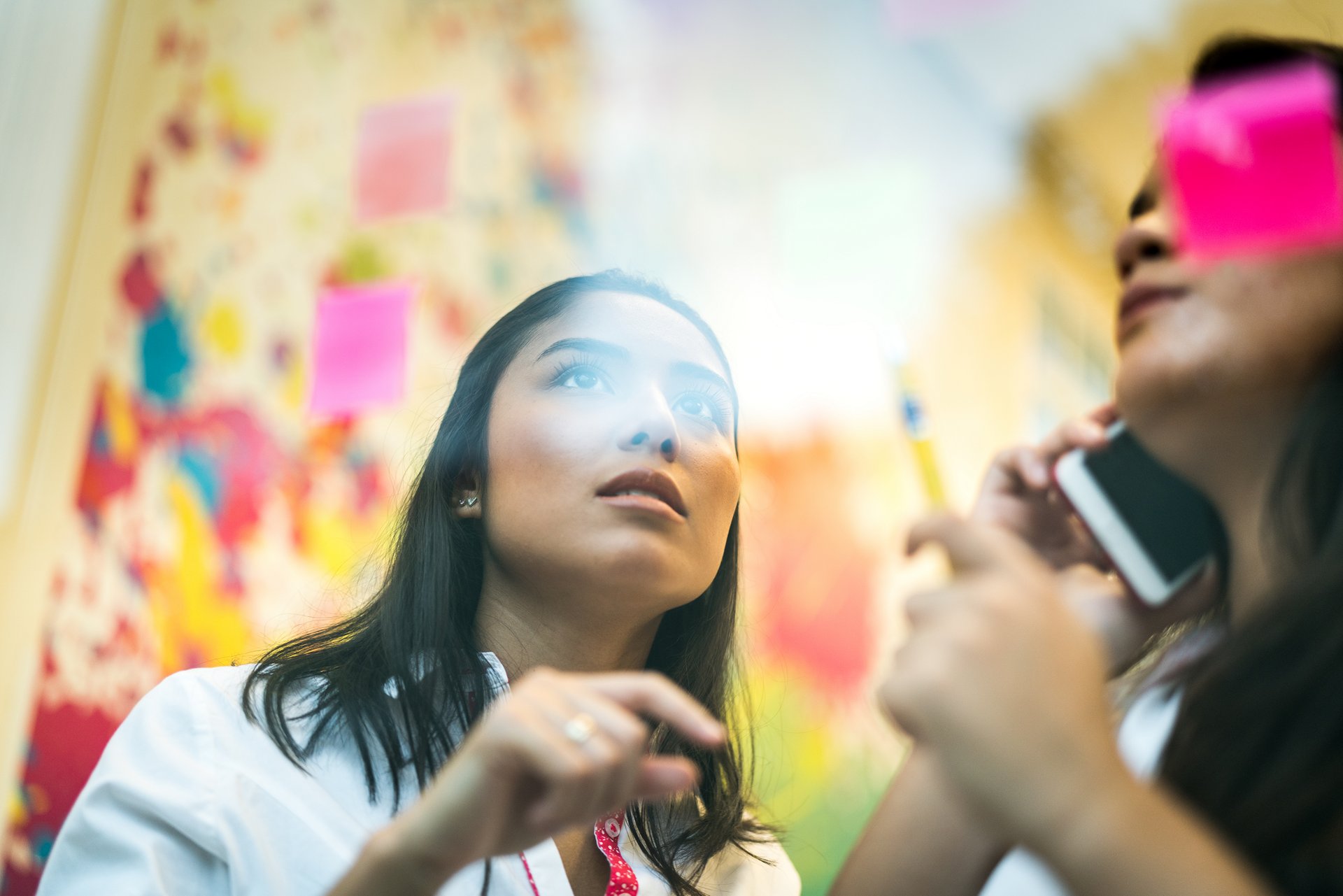 Two business women working together on wall glass