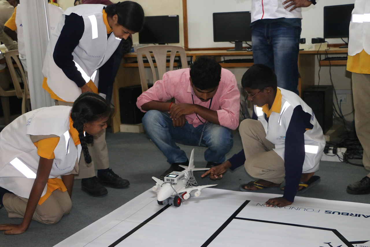 Students gather around their aviation-focussed science project during an Airbus Little Engineer event in Bengaluru, Indira.