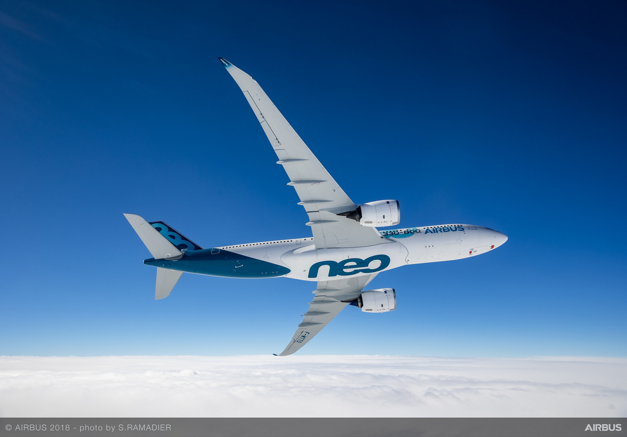 An in-flight photo of a banking Airbus A330neo commercial aircraft.