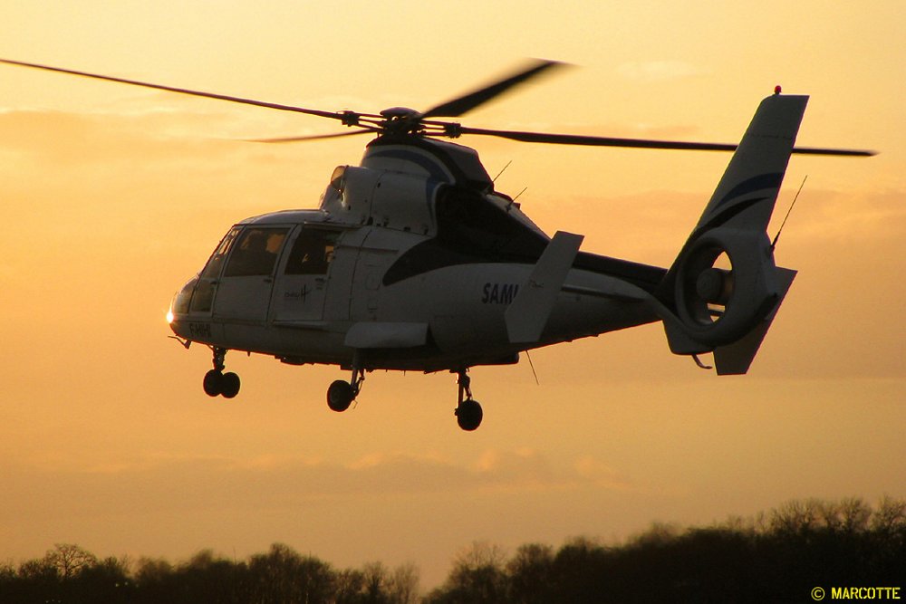 A rear view of a Mont Blanc Helicopters-operated AS365 flying during sunset. 