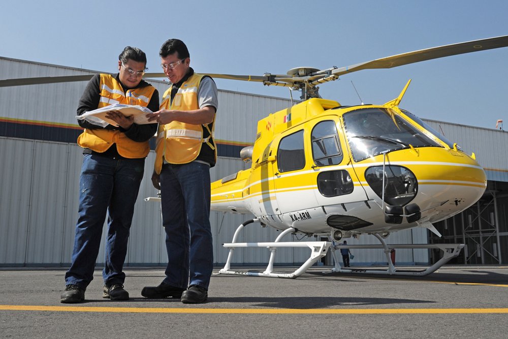 Two engineers review helicopter maintenance documentation. 