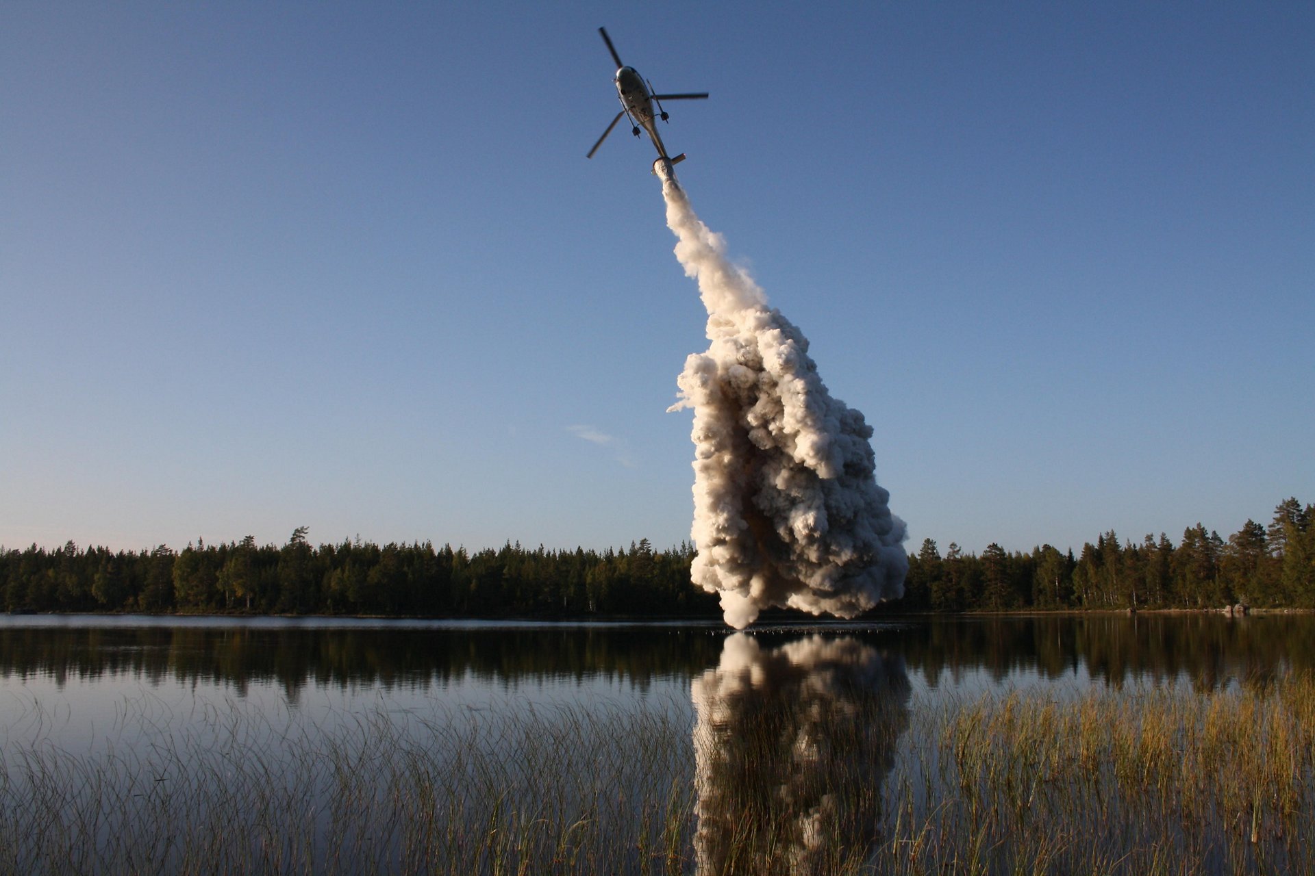 An H125 helicopter operated by Scandair sprays lime over a Scandinavian lake in order to lower freshwater pH levels.