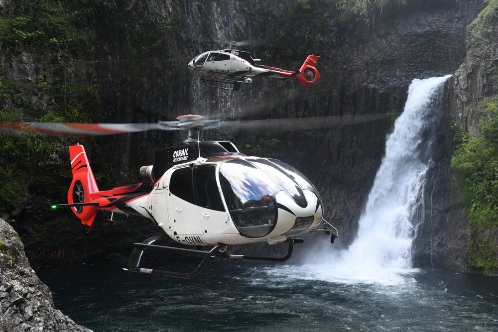 Two Airbus H130 helicopters perform sightseeing missions at a scenic location 