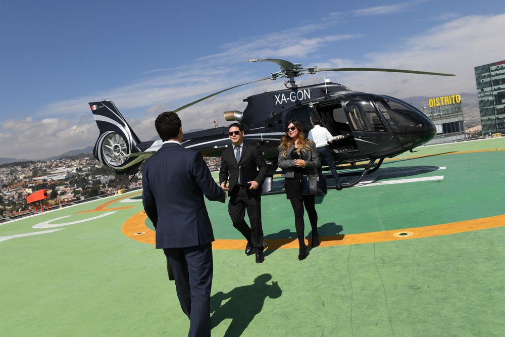 Two professionals walk away after disembarking from an Airbus H130 helicopter tailored for private/business aviation