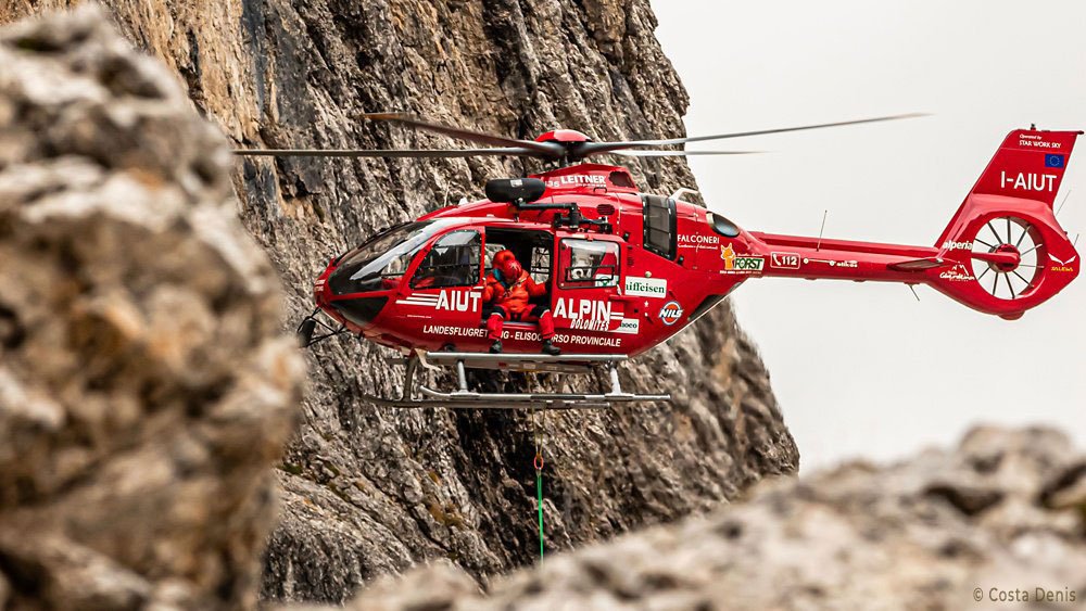 In-flight photo of an H135 helicopter operated by Aiut Alpin Dolomites.