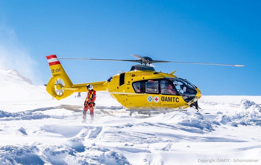 An Airbus-produced H135 helicopter flown by HEMS operator ÖAMTC is shown after landing on snow-covered terrain. 