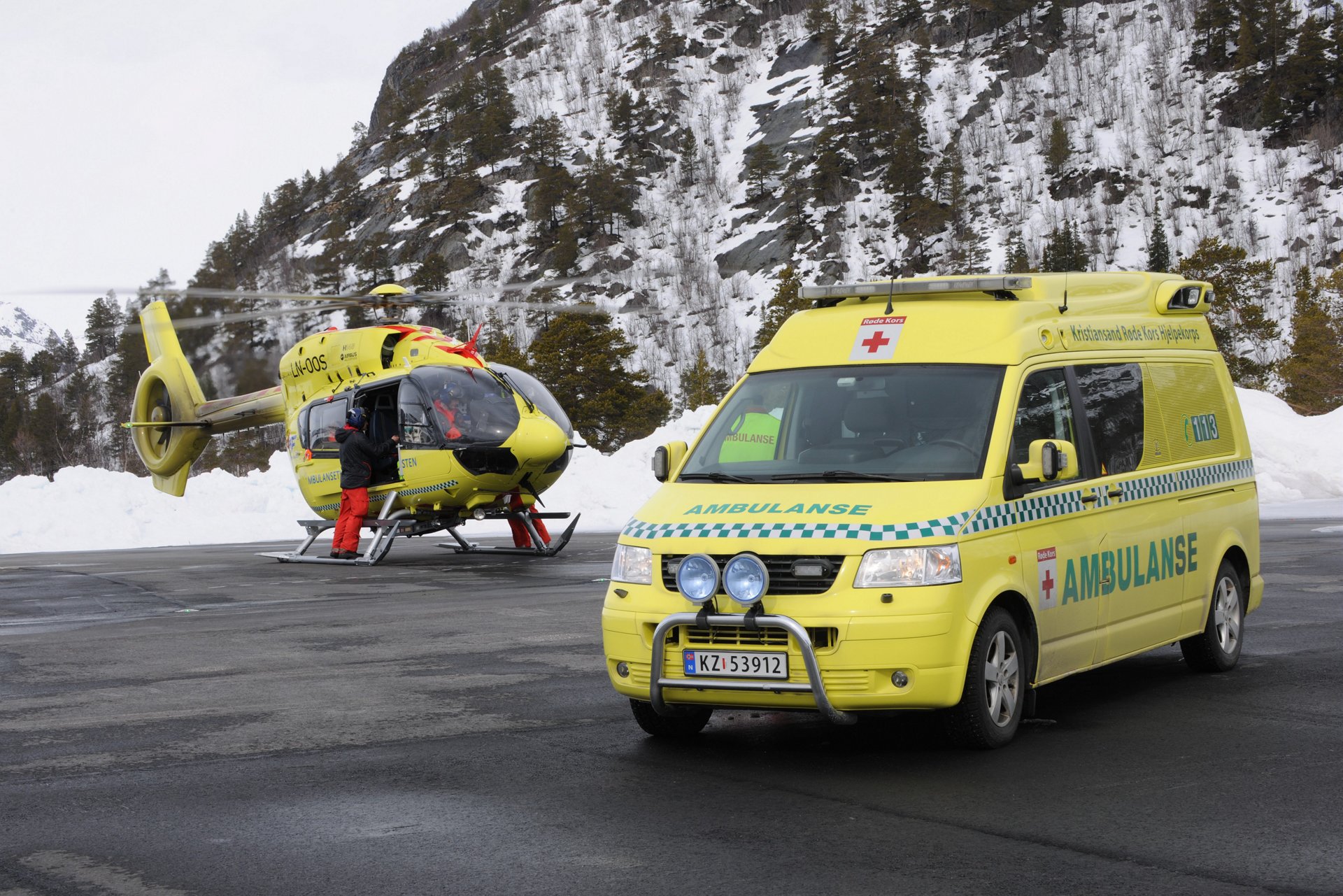 An Airbus helicopter on the ground with ambulance in the foreground.