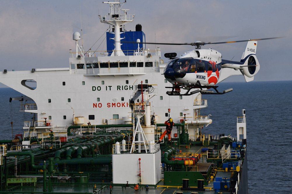 An Airbus H145 helicopter descends for landing on a ship.  