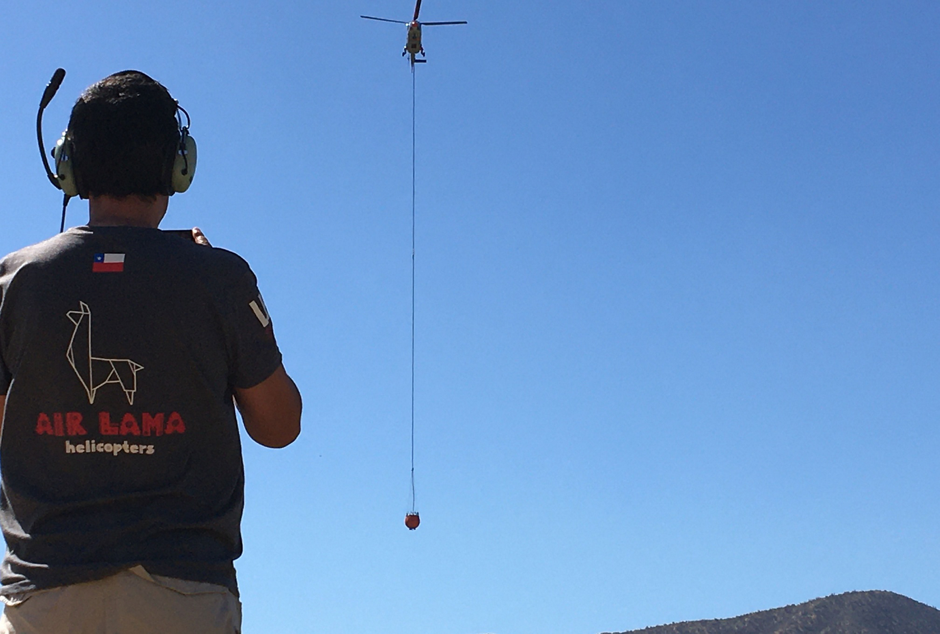 An Airbus H215 helicopter carries a bucket-type water dispersal system in Chile.