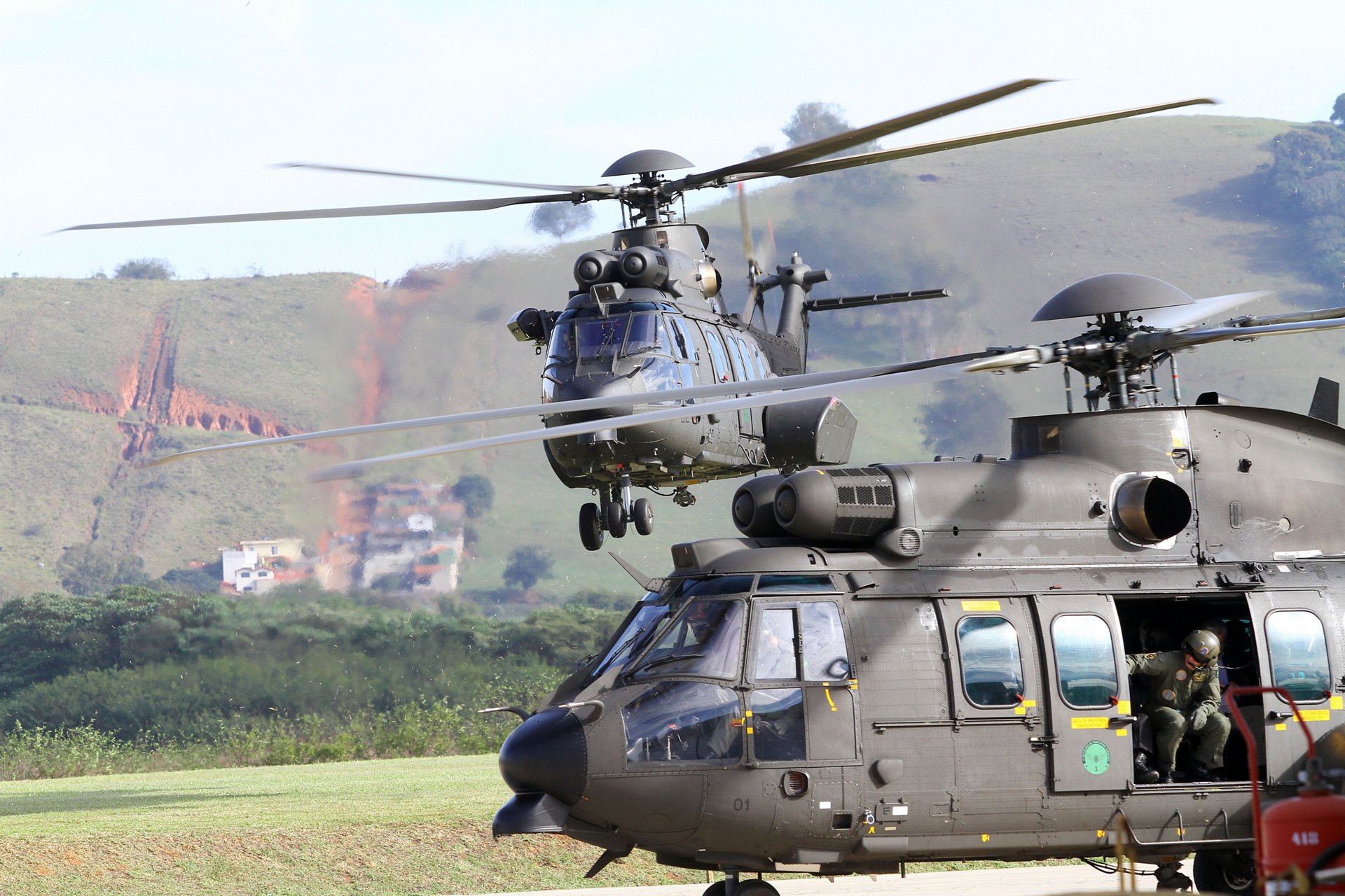 An H225M is shown in flight, with another on the ground. 