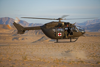 A U.S. Army UH-72A Lakota  from the USAAAD (Fort Irwin, California) cruises over the desert past a M1A2 Abrams main battle tank