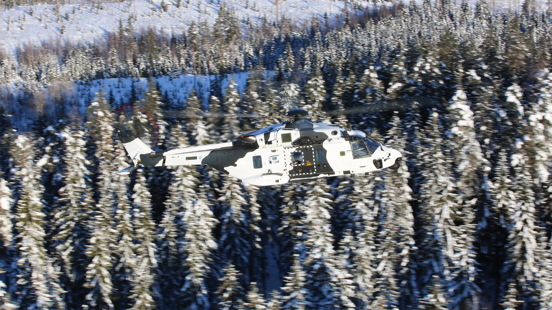 A Finnish Army NH90 is shown in flight with a camouflage paint scheme.  