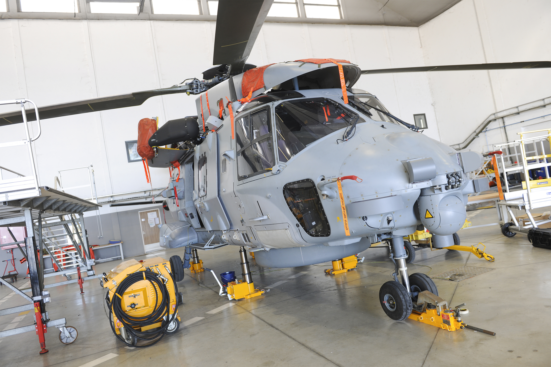 An NH90 helicopter is shown inside a maintenance facility, ready for servicing. 