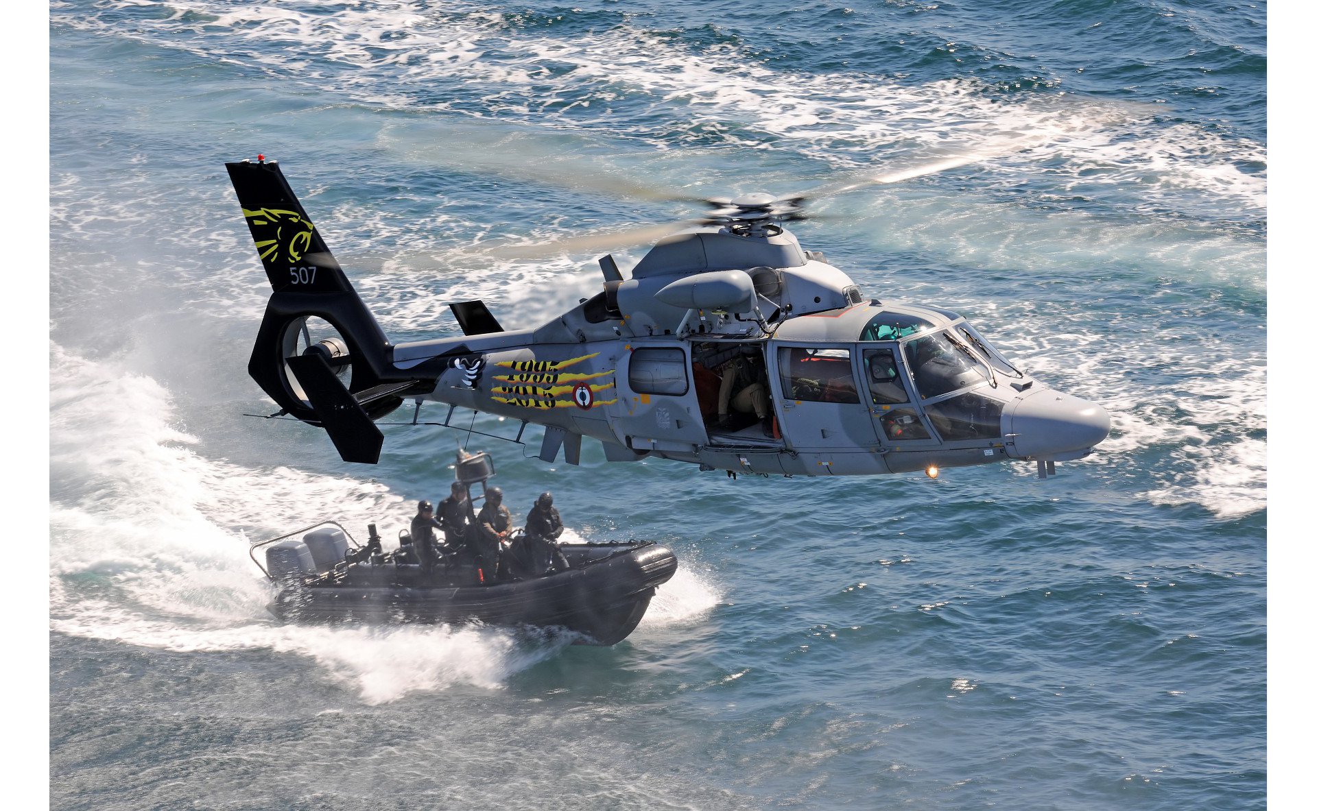 An Airbus AS565 MBe military helicopter of the French Navy flies over a vessel with commandos. 