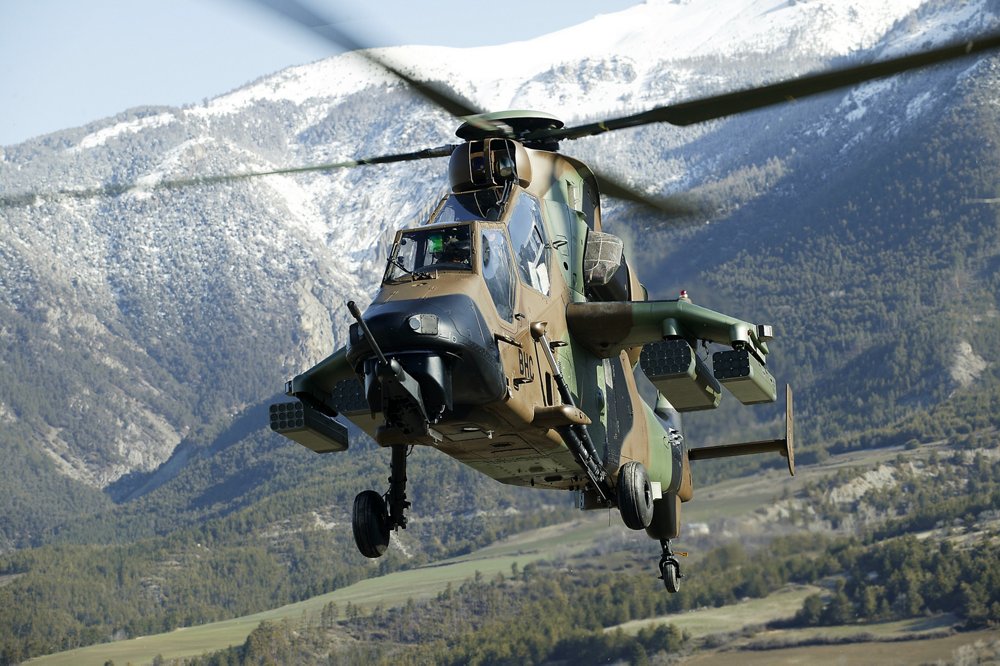 An Airbus-produced Tiger combat helicopter flies in a mountainous area.  
